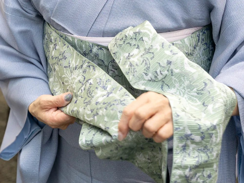 半幅帯を手に、帯結びを教わっている様子